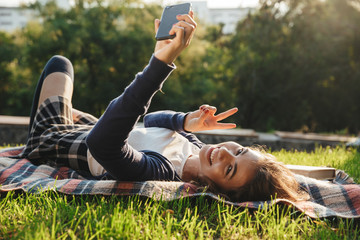 Poster - Cheerful teenage girl laying on a blanket at the park