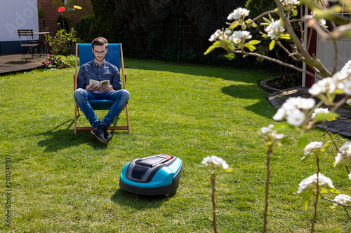 Person Im Liegestuhl Neben Mahroboter Im Garten Buy This Stock
