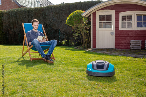 Person Im Liegestuhl Neben Mahroboter Im Garten Buy This Stock