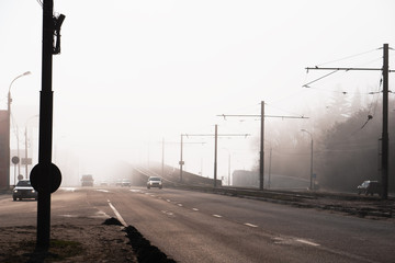 City road or street with car traffic in morning spring fog or haze, atmospheric urban photo