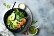 Detox Buddha bowl with avocado, spinach, greens, zucchini noodles, grilled shrimps and pesto sauce. Vegetarian vegetable low carb lunch bowl.