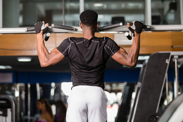 Wall Mural - Black African American  young man doing pull up workout at the gym