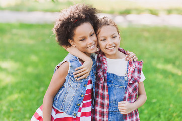 Wall Mural - Two little girls hugging in the park. Kids friends playing together outdoor. Summer fun, vacations concept