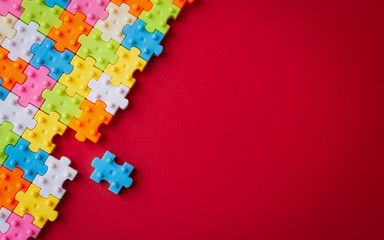 Colors plastic jigsaw puzzle on red paper background, Missing one jigsaw puzzle to complete with copy space.