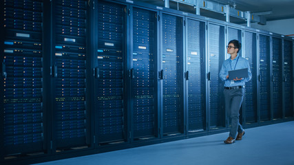 Wall Mural - In Data Center: Male IT Technician Running Maintenance Programme on a Laptop, Controls Operational Server Rack Optimal Functioning. Modern High-Tech Telecommunications Operational Super Computer.