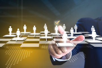 Business administrator selecting a man in action of manpower or human resource planning or business organisation on a virtual checkerboard or draughtboard.