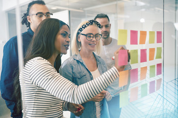 Smiling coworkers brainstorming with sticky notes in an office