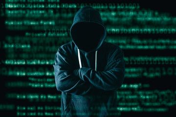 the abstract image of the hacker standing and the binary code image is backdrop. the concept of cybe