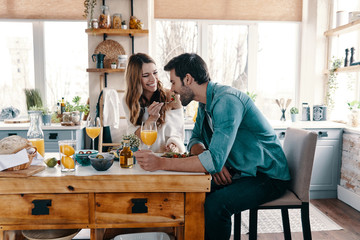 Sticker - Try it! Beautiful young couple enjoying healthy breakfast while sitting in the kitchen at home