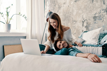 Wall Mural - Just being around. Beautiful young couple using computer while spending time in bed at home