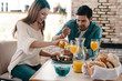 © gstockstudio - Good meal in a good company. Beautiful young couple enjoying healthy breakfast while sitting in the kitchen at home