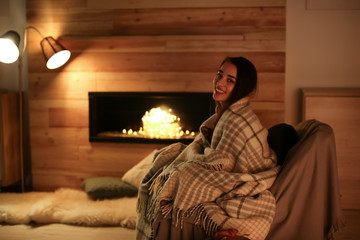 Sticker - Young woman resting near decorative fireplace at home. Winter season