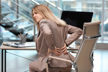 Wall Mural - Young woman suffering from back pain in office