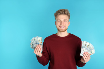 Wall Mural - Young man with money on color background. Space for text