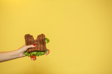 Woman Hands Hold Bitten Sandwich On Yellow Background. Sandwich Promotion Concept
