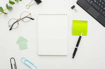 Wall Mural - Top view of office workplace with blank spiral notepad, glasses, supplies and sticky notes. Mock up