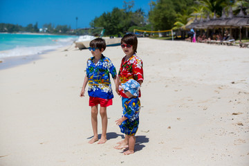 Canvas Print - Happy beautiful fashion children, dressed in hawaiian shirts, playing together on the beach