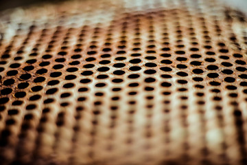 Wall Mural - Perforated brown rusty iron sheet texture. Surface with depth of field, industrial mesh. Horizontal background