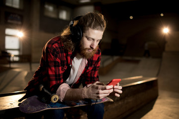 Wall Mural - Portrait of bearded man using smartphone while sitting on ramp in extreme park, shot with flash