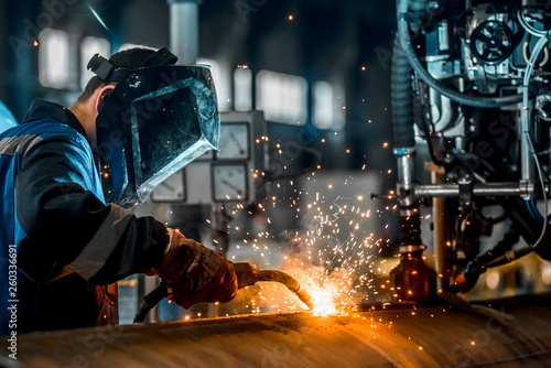 Fotografía man welds at the factory