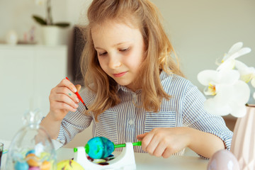 Cute little blonde girl painting Easter eggs