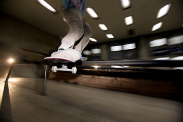 Wall Mural - Action shot of unrecognizable young man doing skating stunt flying in air at skateboard park, shot with flash