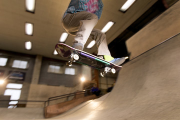 Wall Mural - Action shot of anonymous young man doing skating trick flying in air at skateboard park, shot with flash