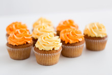 Food, Pastry And Confectionery Concept - Cupcakes With Buttercream Frosting Over White Background