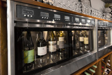 Alcohol, Technology And Storage Concept - Close Up Of Wine Bottles Storing In Dispenser At Bar Or Restaurant