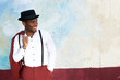 © mimagephotos - cool african american male fashion model smiling with vintage suit, suspenders and hat by wall