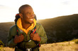 © mimagephotos - Close up handsome young african american man with backpack smiling with sunset in background