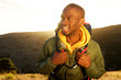 © mimagephotos - Close up handsome young african american man with backpack smiling with sunrise in background