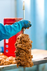 Wall Mural - Workers impale the meat on a skewer making preparations from chicken fillet in production. Vertical photography