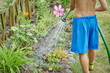 © Artem - European boy is helping his father to water the flowers in the garden.