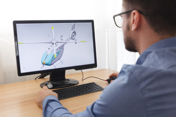 Engineer, Constructor, Designer in Glasses Working on a Personal Computer. He is Creating, Designing a New 3D Model of Helicopter in CAD Program. Freelance Work