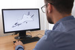 © vladim_ka - Engineer, Constructor, Designer in Glasses Working on a Personal Computer. He is Creating, Designing a New 3D Model of Aircraft, Airplane in CAD Program. Freelance Work