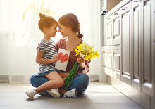 Happy Mother's Day! Child Daughter   Gives Mother A Bouquet Of Flowers To Narcissus And Gift.