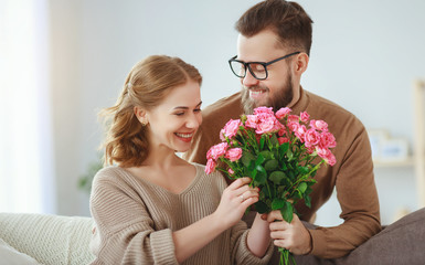 happy loving   couple. husband gives his wife flowers at home    .