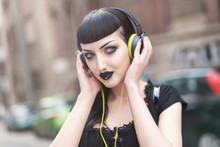 Urban Goth Girl Listening To Her Favourite Music Over Her Big Headphones, Street In A City Surroundings