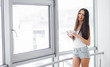 © Maksymiv Iurii - Happy morning. Portrait of beautiful young woman standing at window, drinking coffee and looking outside enjoys of rest