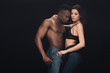 © LIGHTFIELD STUDIOS - attractive woman embracing shirtless african american man and holding condom isolated on black