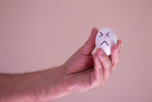 A Man Holding An Egg With A Funny Face. Conceptual Image