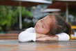 © zilvergolf - Sassy little Asian child girl with funny face lying on the wooden table.
