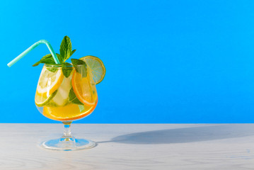 Wall Mural - .Refreshing cocktail with orange lemon lime mint and ice on a bright blue background