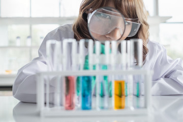 Wall Mural - a young asian woman scientist working in laboratory holding magnifying glass with test tubes and sol