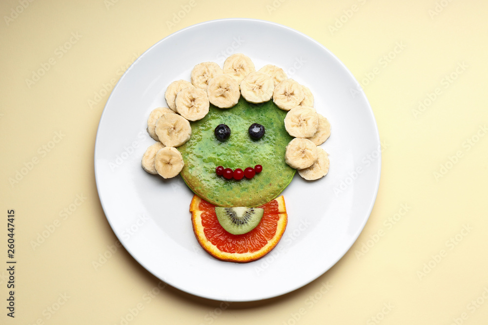 Plate with tasty green pancake for kid on color background