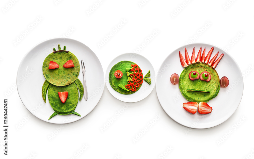 Plates with tasty green pancakes on white background