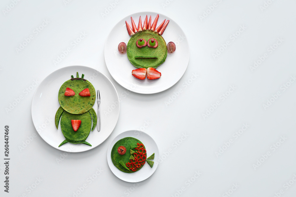 Plates with tasty green pancakes on white background