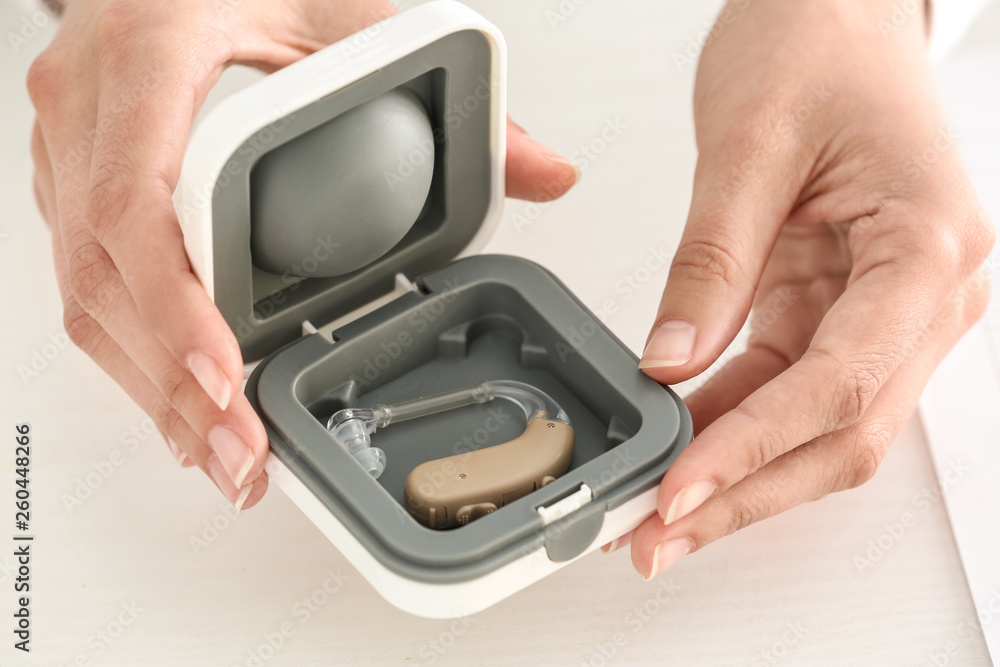 Female doctor holding box with hearing aid
