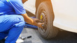 The car mechanic replacing flat tires on the road. Blue hydraulic car floor jacks lift the cars and wheel wrench placed nearby as background. Car repair, sevice engine and maintenance concept.